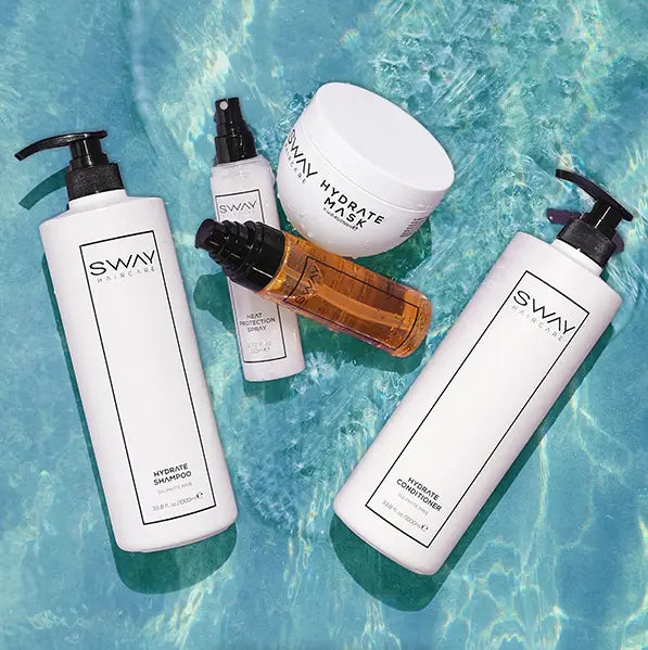 Products in water: SWAY Travel Trio. Keep hair hydrated on holiday with SWAY Shampoo and Conditioner. Shop now and decant into travel-friendly minis.